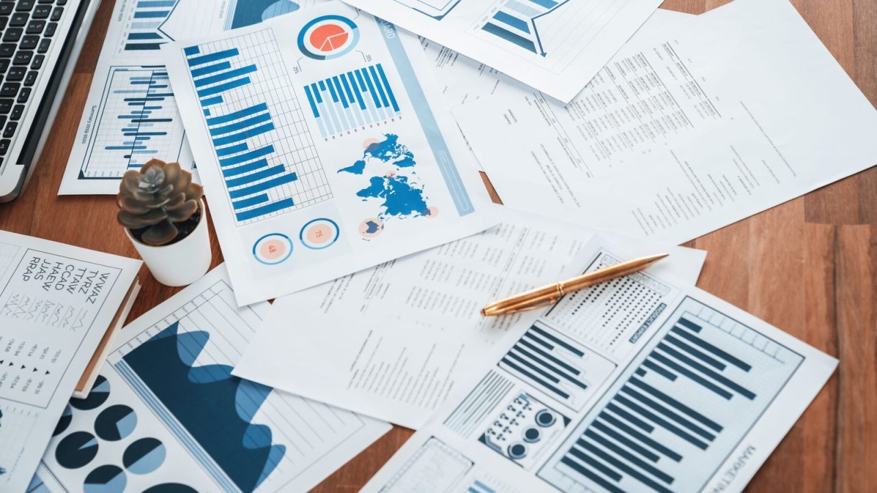 Stacks of printed data reports on a wooden desk