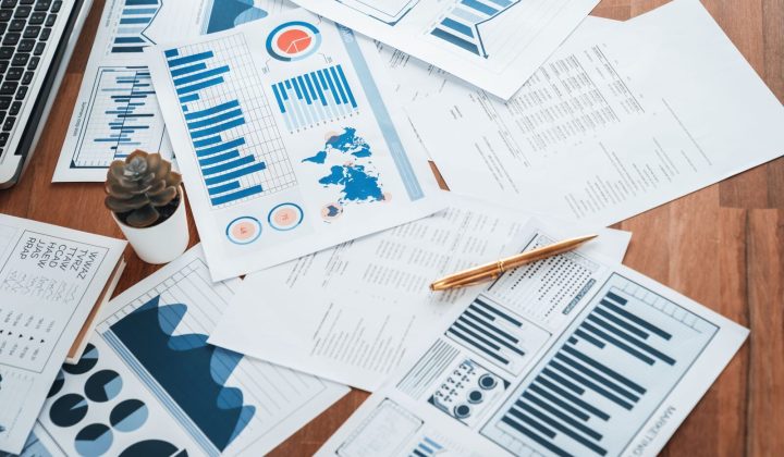 Stacks of printed data reports on a wooden desk